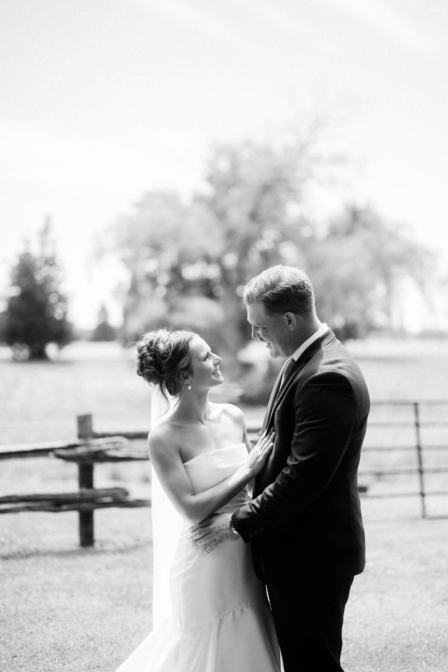 Black and white wedding portrait of bride and groom embracing outdoors on a farm estate near Chatham-Kent, Ontario.