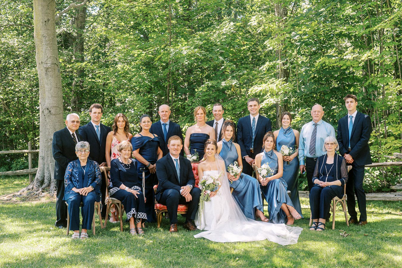 Bride and groom posing with relatives and wedding party outdoors in a wooded private estate setting near Chatham-Kent, Ontario.