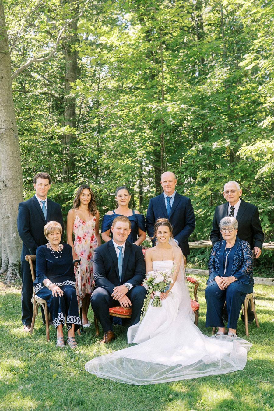 Bride and groom with relatives posing for an outdoor wedding family portrait on a wooded private property near Chatham-Kent, Ontario.