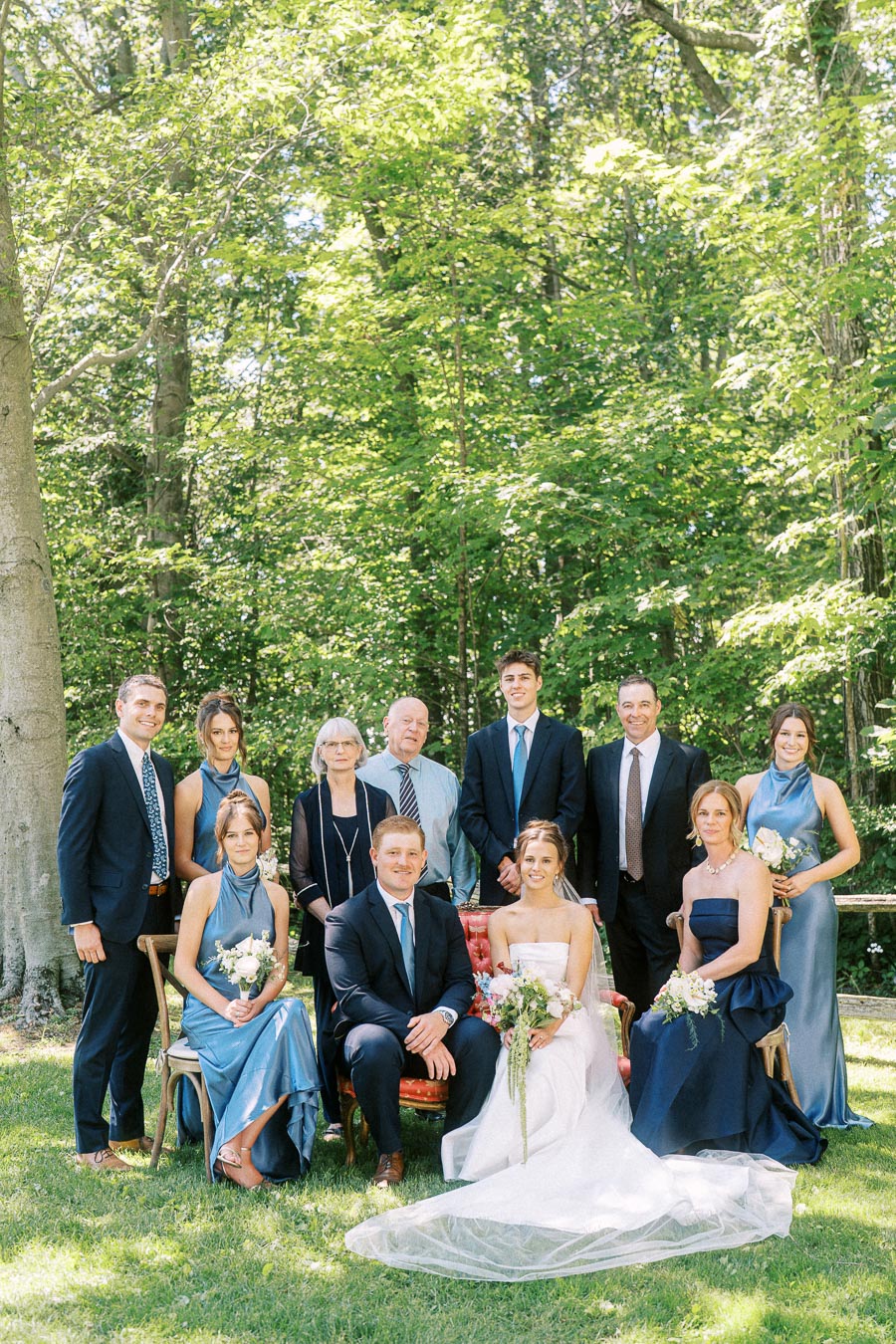 Bride and groom pose with family at an outdoor private estate wedding near Chatham-Kent, Ontario, Canada, surrounded by green woodland.