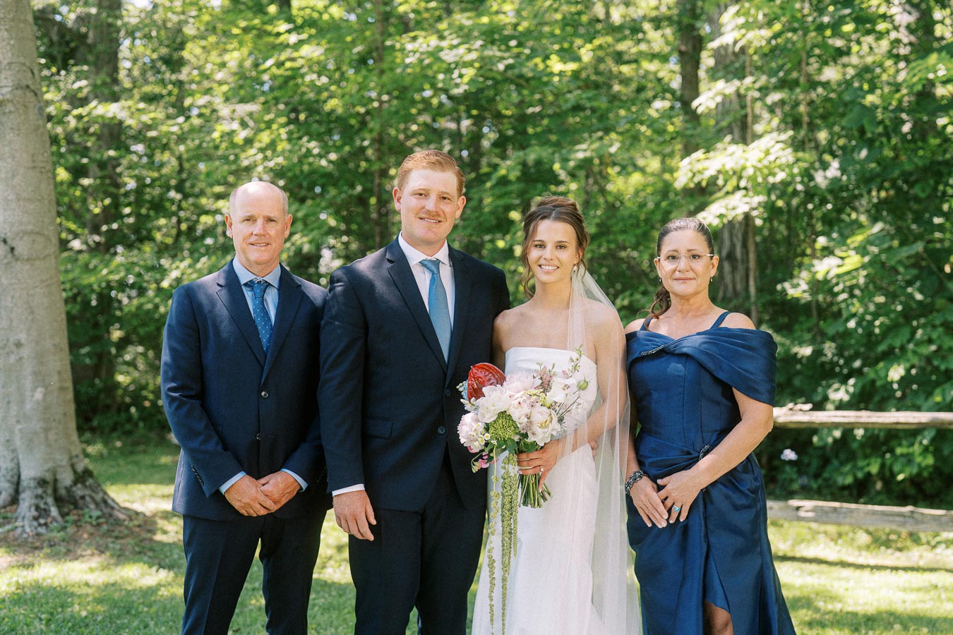 Bride and groom posing with relatives outdoors in a wooded private estate setting near Chatham-Kent, Ontario.