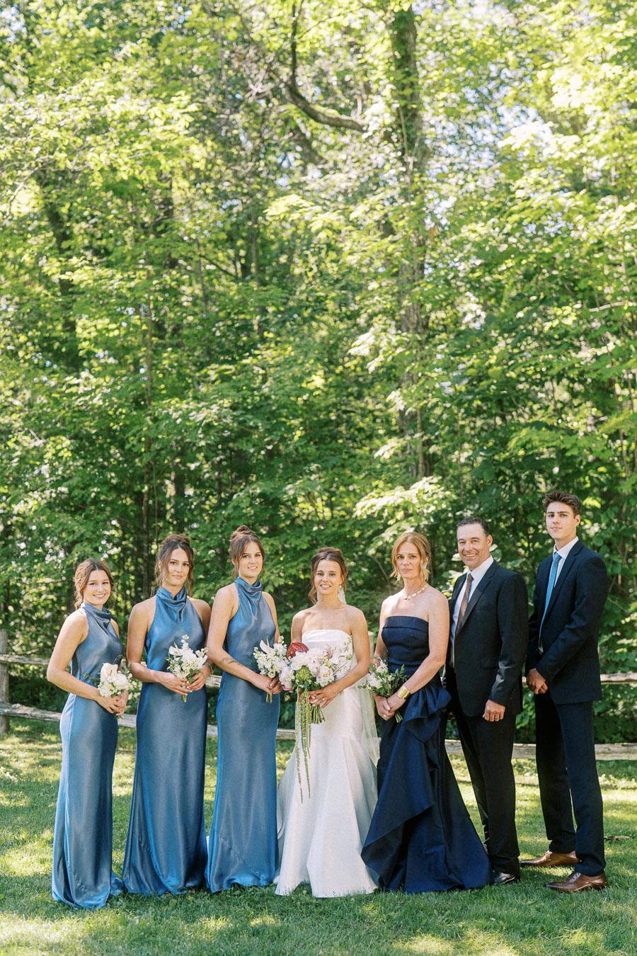 Bride, bridesmaids, and relatives posing for a wedding portrait on a green private estate lawn near Chatham-Kent, Ontario, Canada.