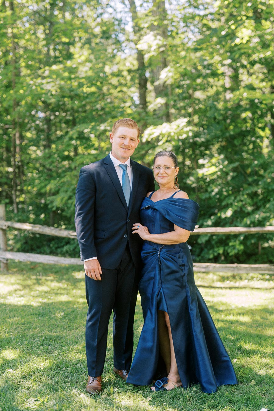 Man in a navy suit and woman in a blue formal dress posing outdoors on grass near Chatham-Kent, Ontario.