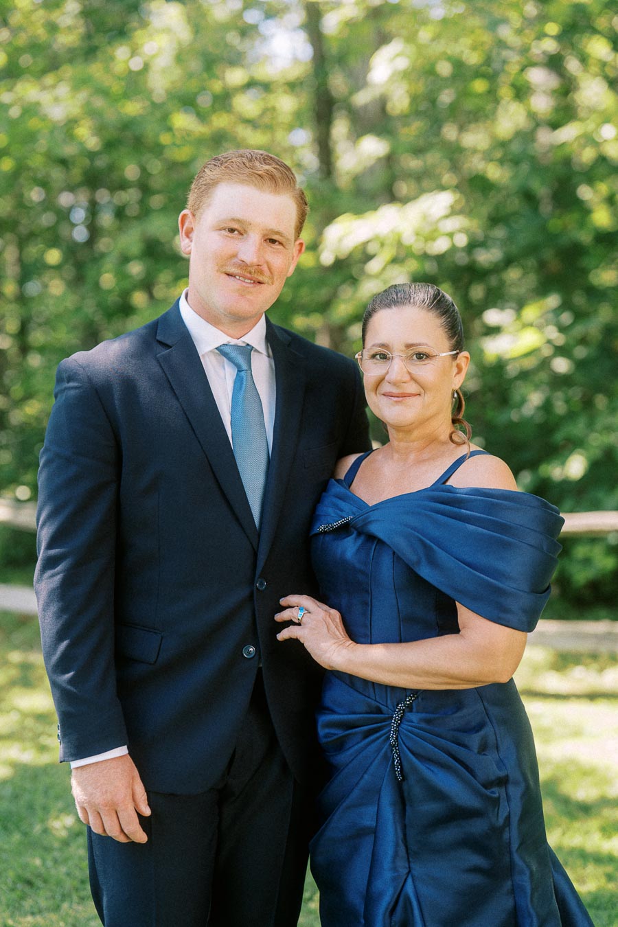 Formal wedding portrait of a man in a navy suit and woman in a blue dress outdoors near Chatham-Kent, Ontario, Canada.