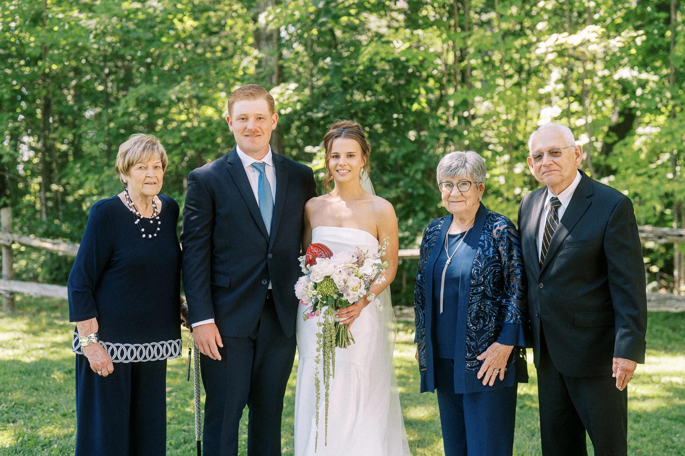 Bride and groom posing with older relatives outdoors on a wooded private property near Chatham-Kent, Ontario.
