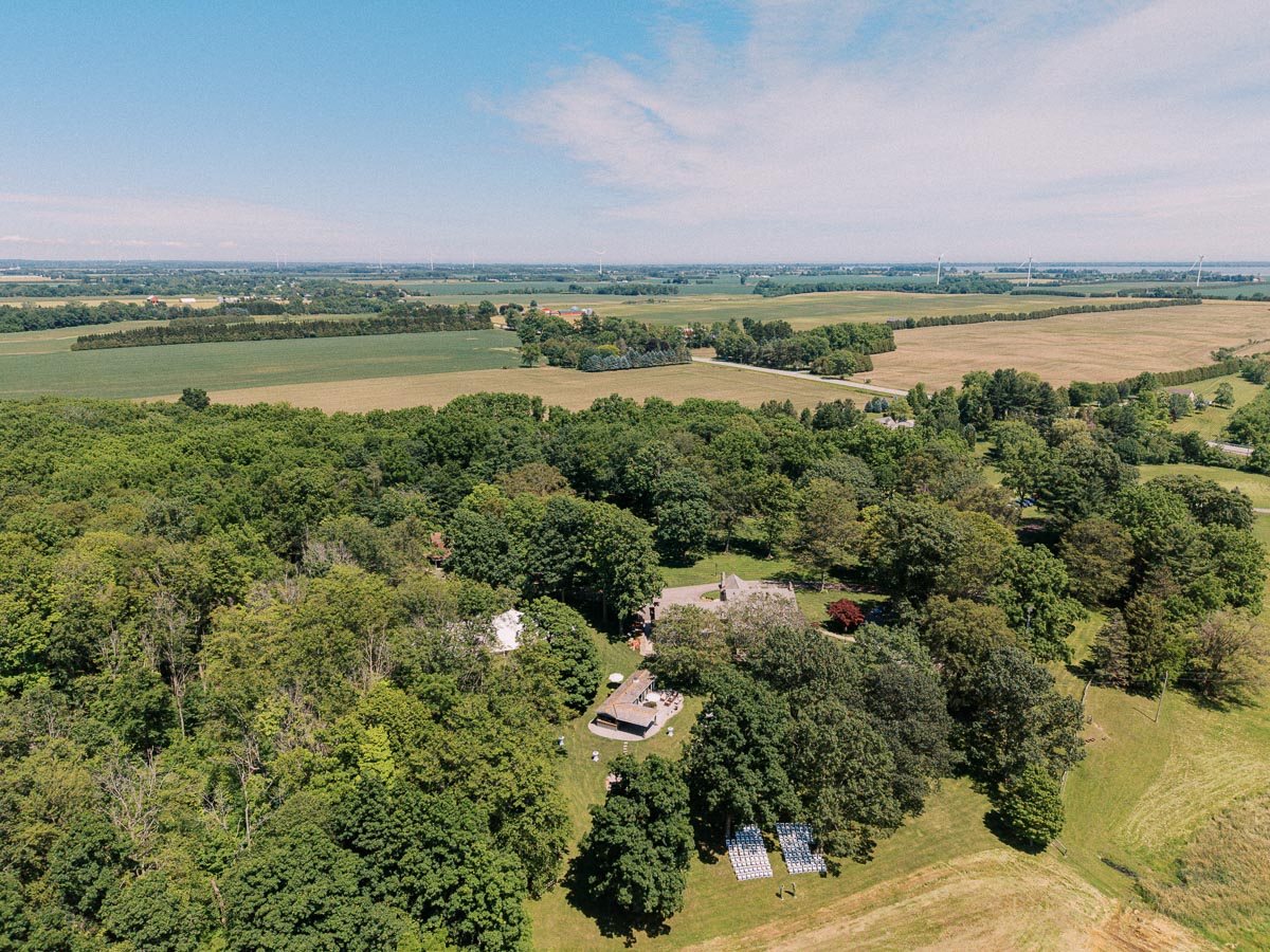 Aerial view of a private estate wedding ceremony setup on a lawn surrounded by trees and farm fields near Chatham-Kent, Ontario, Canada.