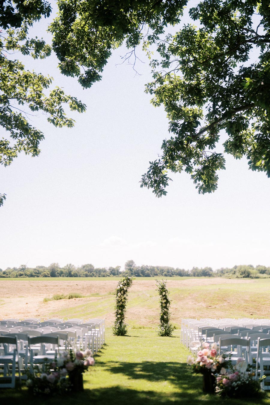 Outdoor wedding ceremony setup with white chairs, floral aisle arrangements, and greenery arches on a private estate lawn near Chatham-Kent, Ontario.