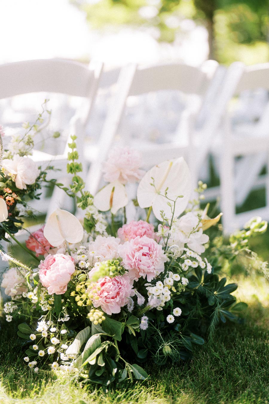 Pastel floral wedding arrangement with pink flowers and white chairs at an outdoor ceremony in Chatham-Kent, Ontario, Canada.