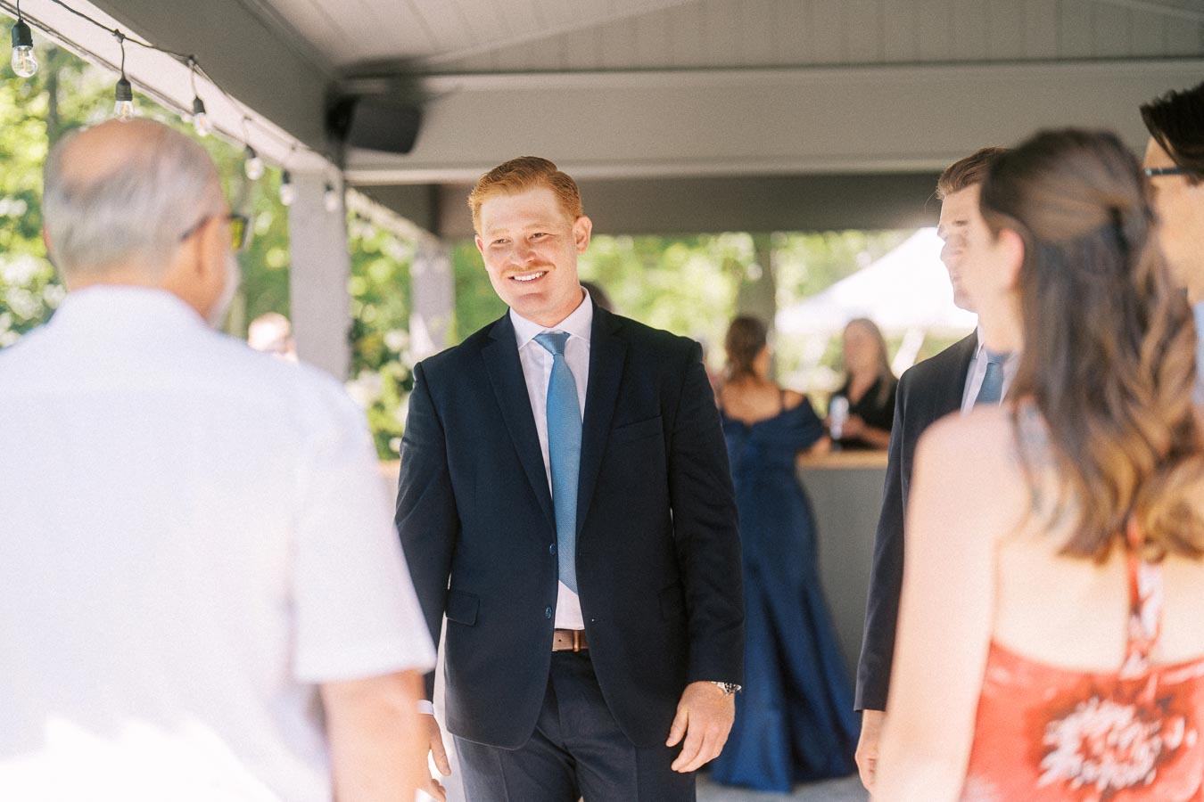 Wedding guests talking during cocktail hour under a tent at a private estate near Chatham-Kent, Ontario, Canada.