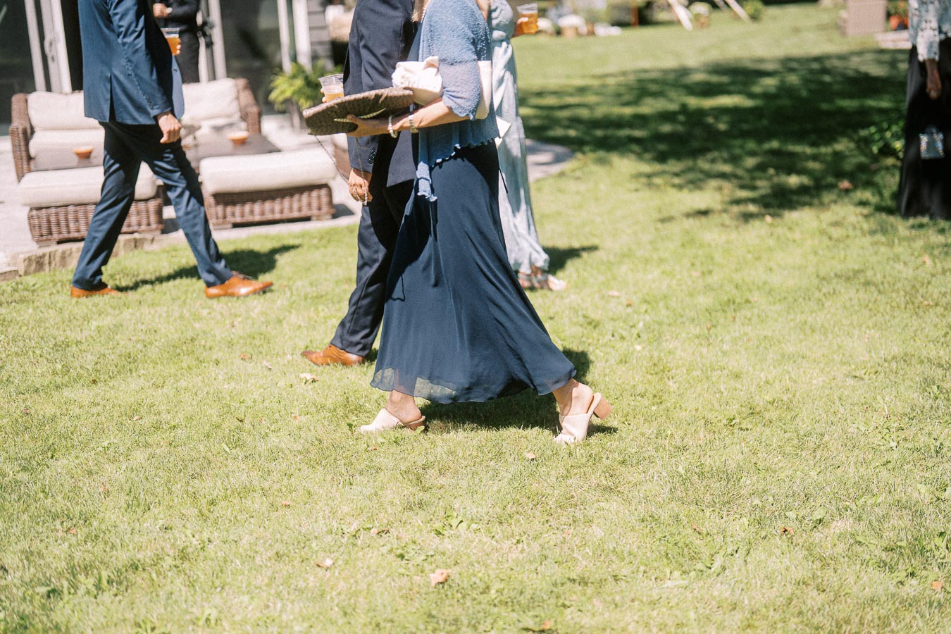 Wedding guests walking on a sunny lawn during cocktail hour at a private estate near Chatham Kent, Ontario, Canada.