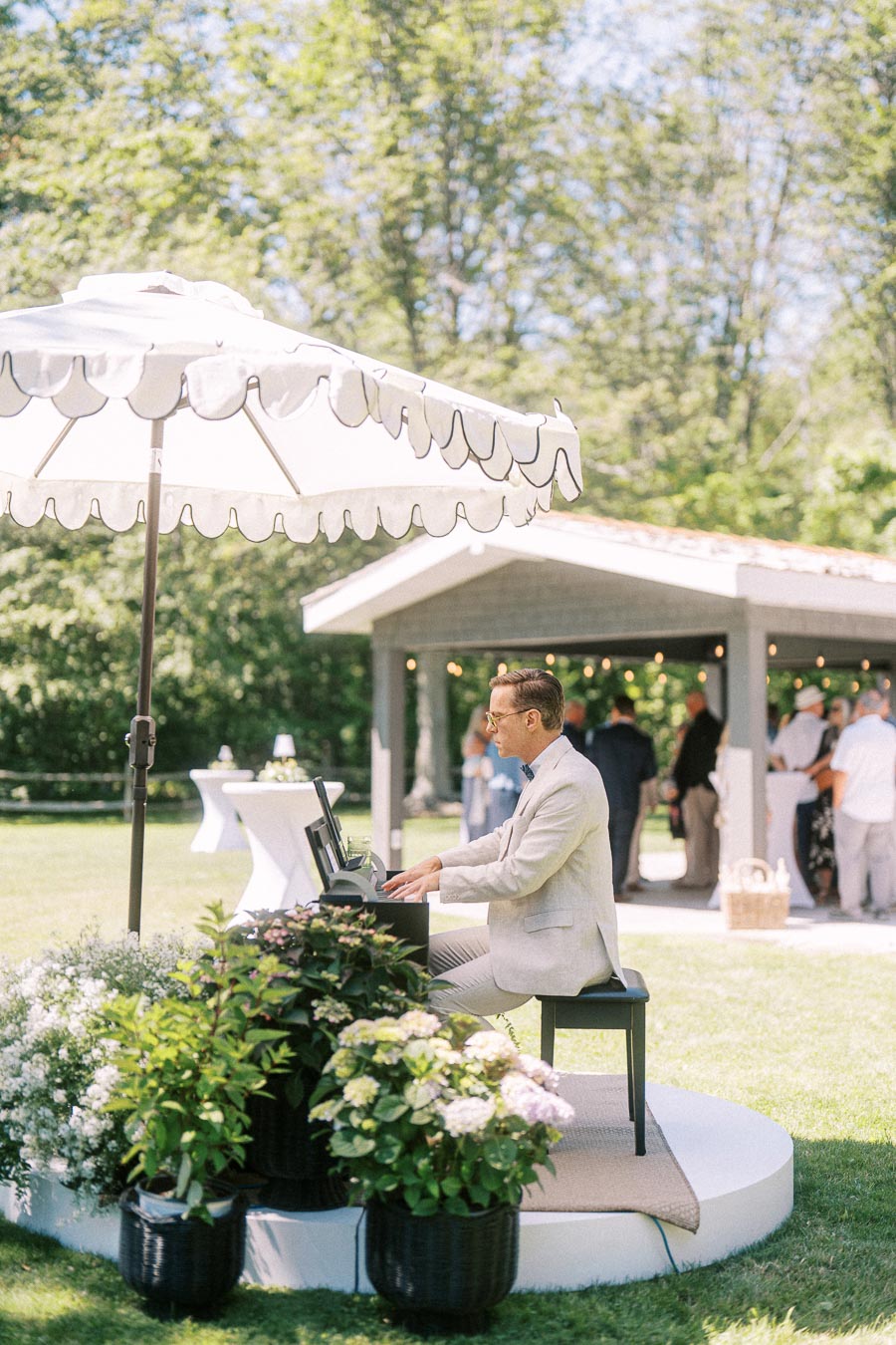 Pianist performing under a white umbrella at an outdoor private estate wedding cocktail hour near Chatham-Kent, Ontario.