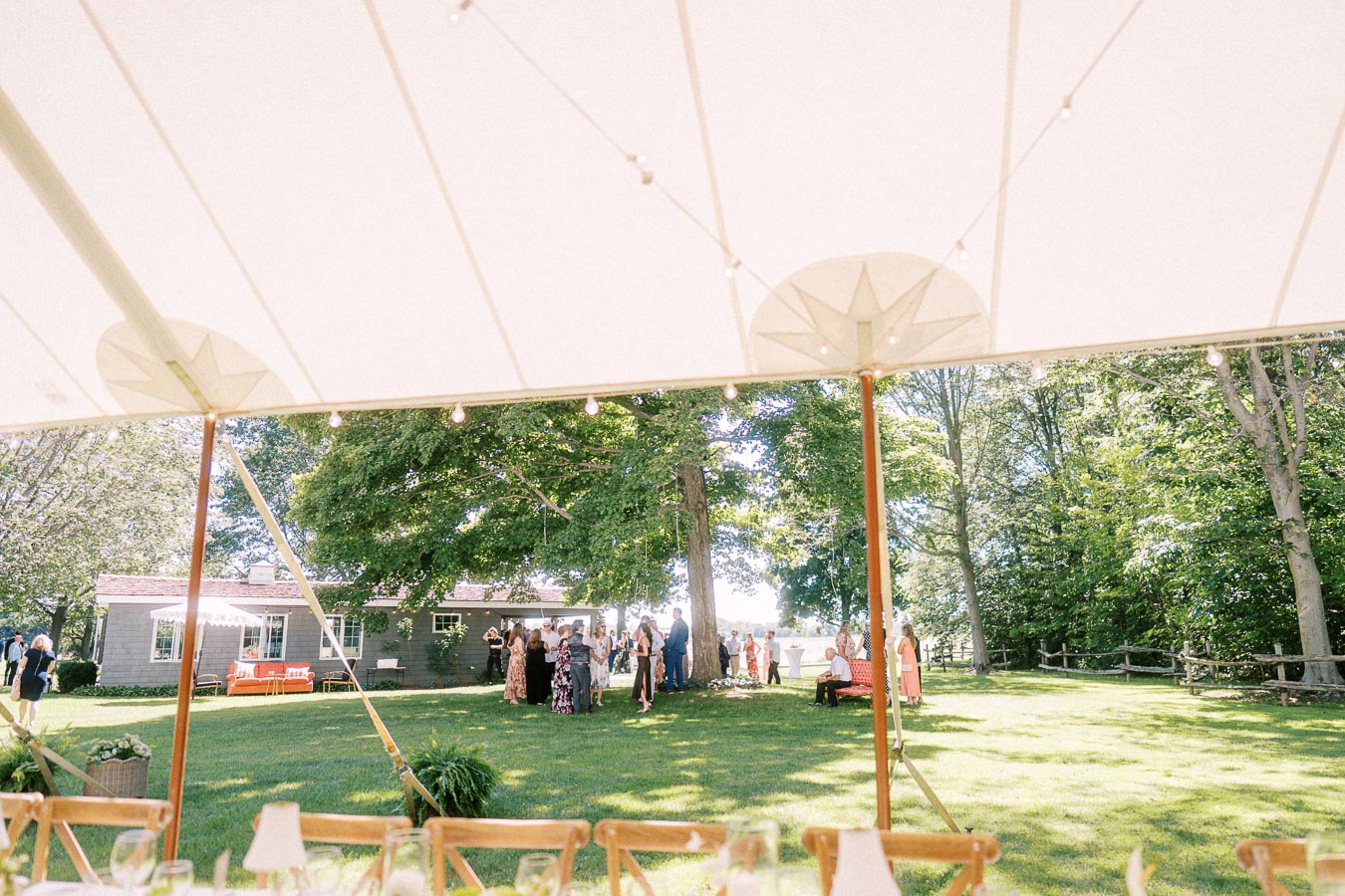 Wedding guests gather on a lawn during cocktail hour under a white tent at a private estate near Chatham-Kent, Ontario.