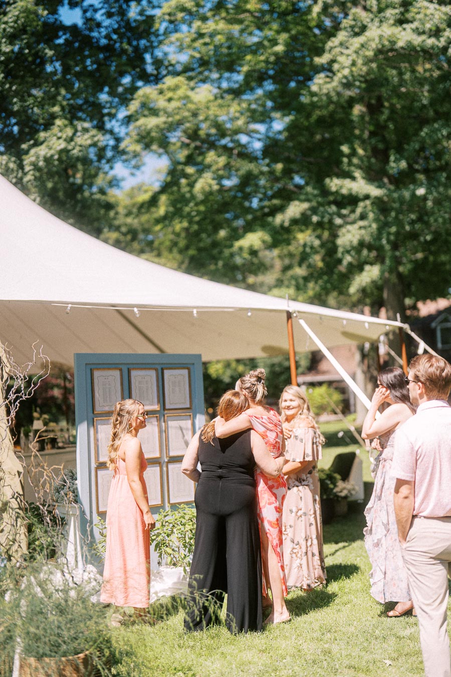 Wedding guests socializing during cocktail hour under a white tent on a private estate lawn near Chatham-Kent, Ontario, Canada.