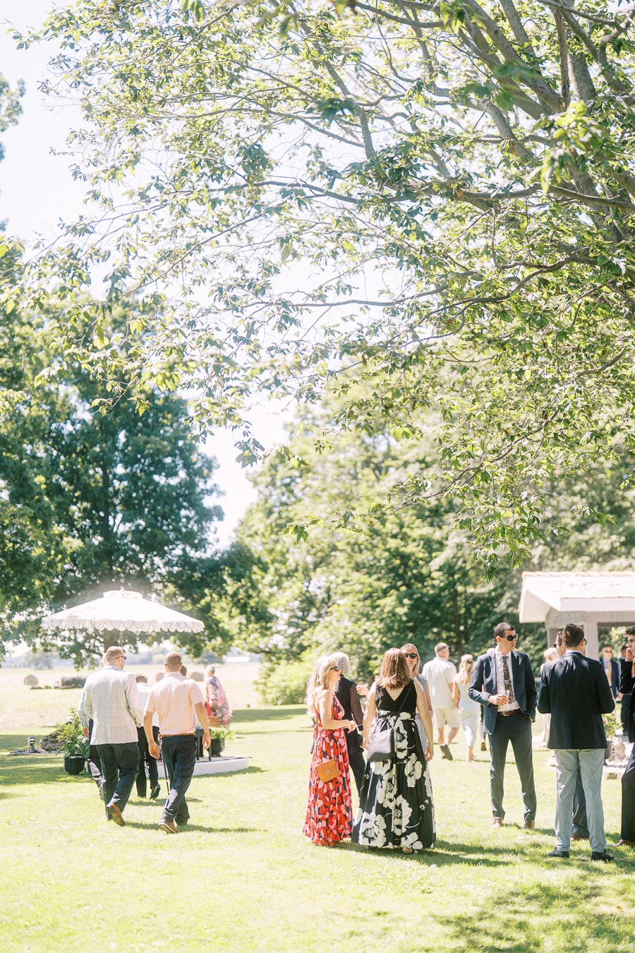 Wedding guests mingle during cocktail hour on a sunny lawn at a private estate near Chatham-Kent, Ontario, Canada.