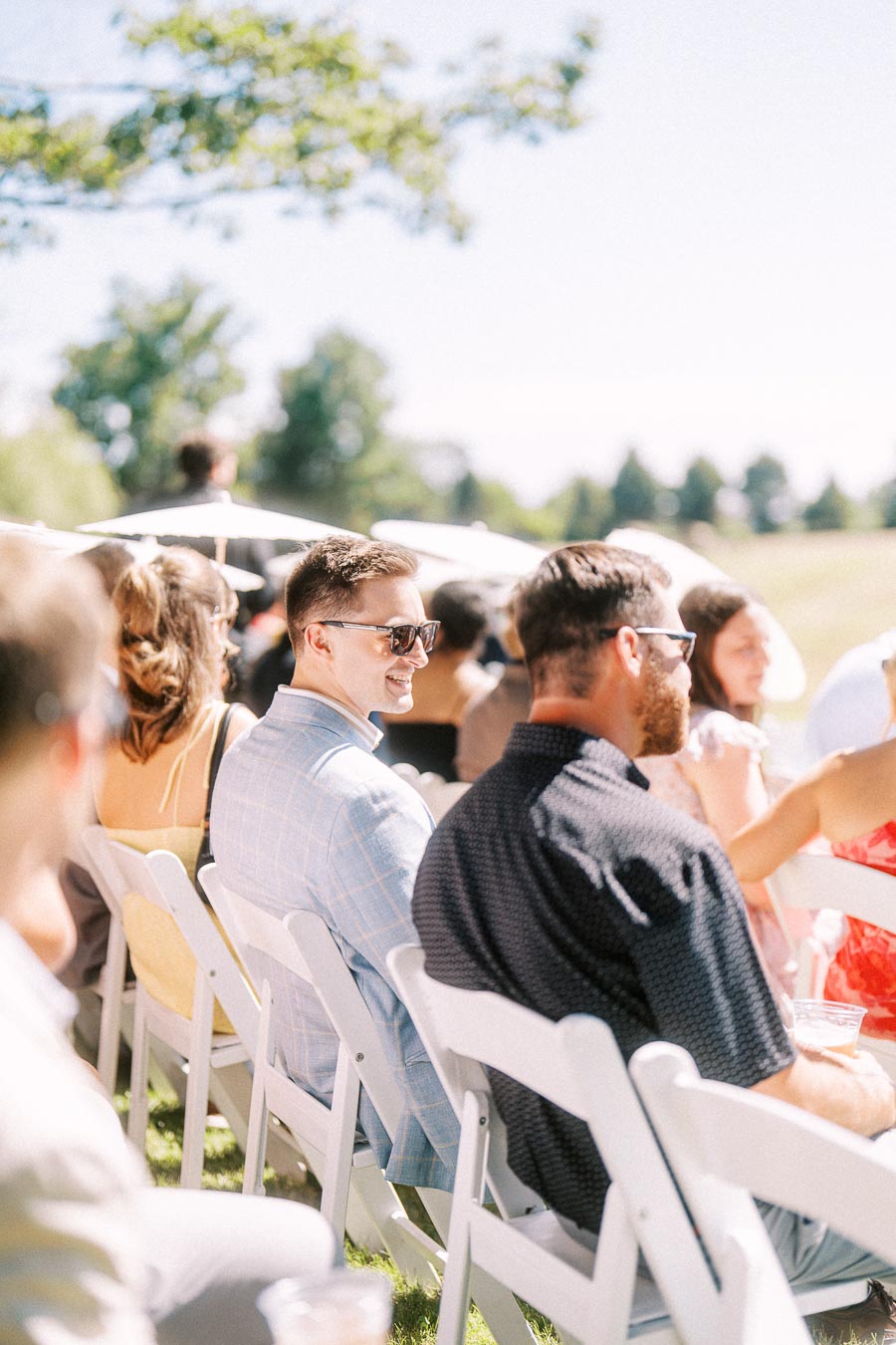Wedding guests seated on white folding chairs during an outdoor private estate ceremony near Chatham-Kent, Ontario, Canada.