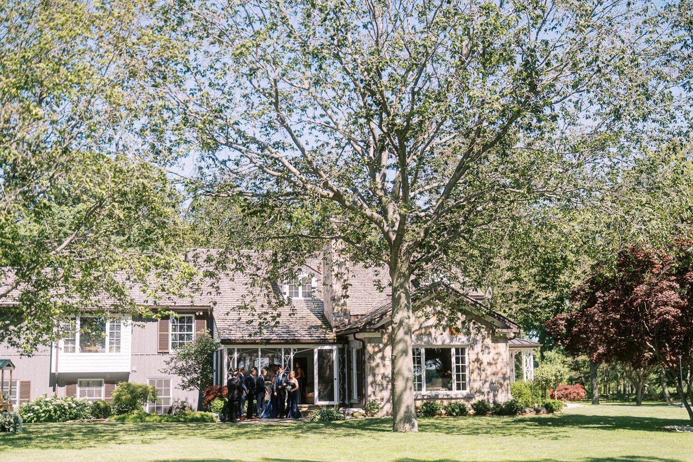 Wedding party standing outside a private estate house under mature trees near Chatham-Kent, Ontario, Canada.