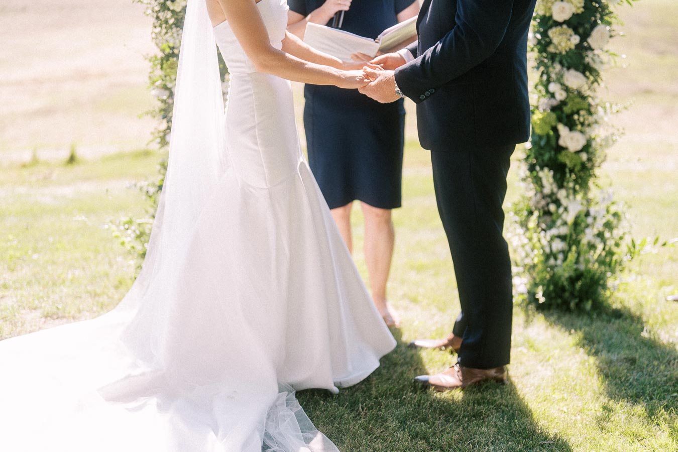 Bride and groom holding hands during an outdoor private estate wedding ceremony near Chatham-Kent, Ontario, Canada.