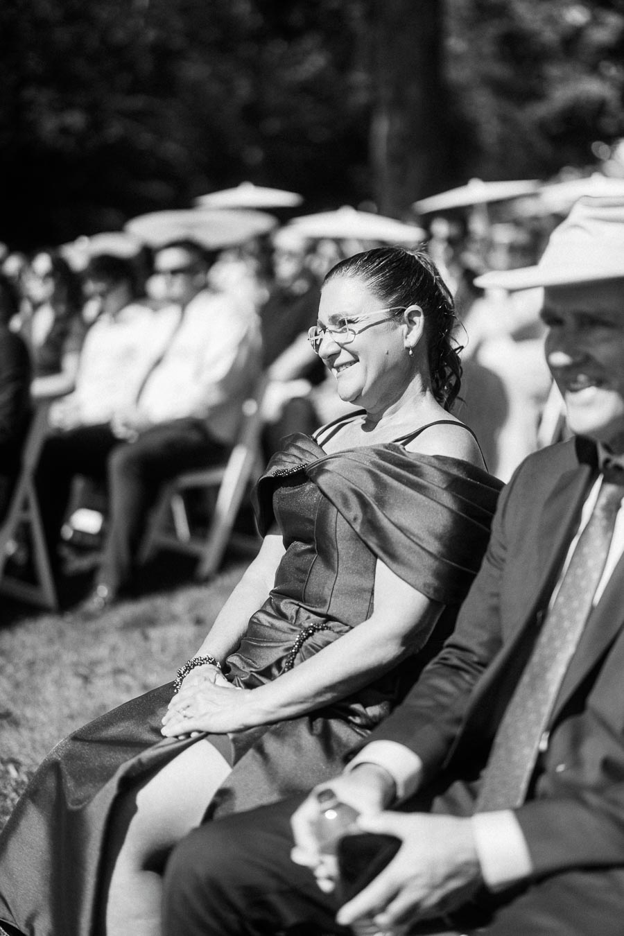 Black and white photo of smiling wedding guests seated outdoors during a ceremony near Chatham-Kent, Ontario.