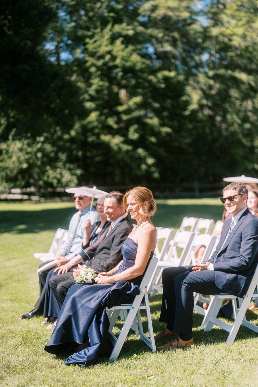 Wedding guests seated on white chairs during an outdoor private estate ceremony on a sunny lawn near Chatham-Kent, Ontario, Canada.