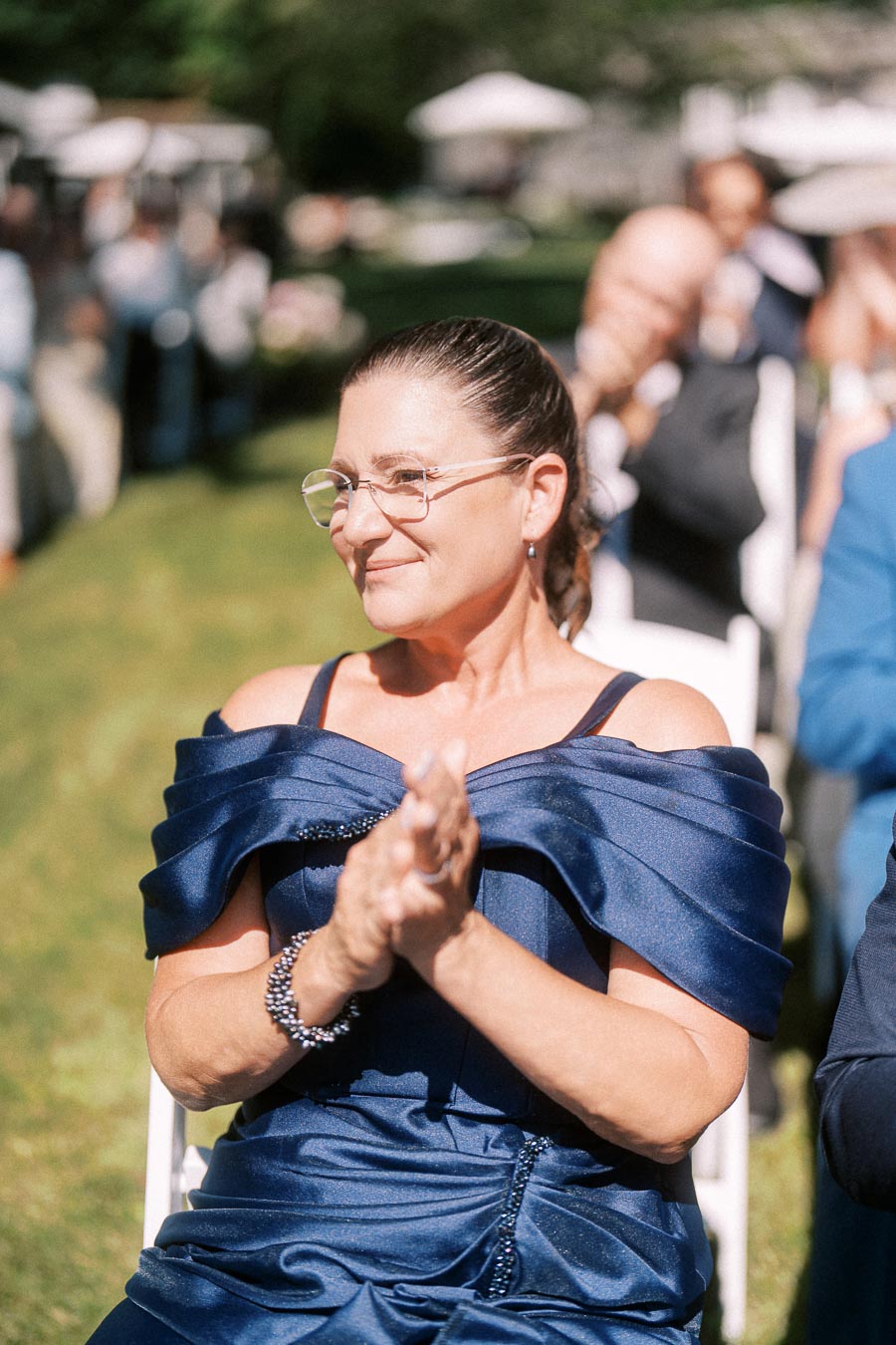 Woman in navy dress applauding during an outdoor wedding ceremony near Chatham-Kent, Ontario, Canada.