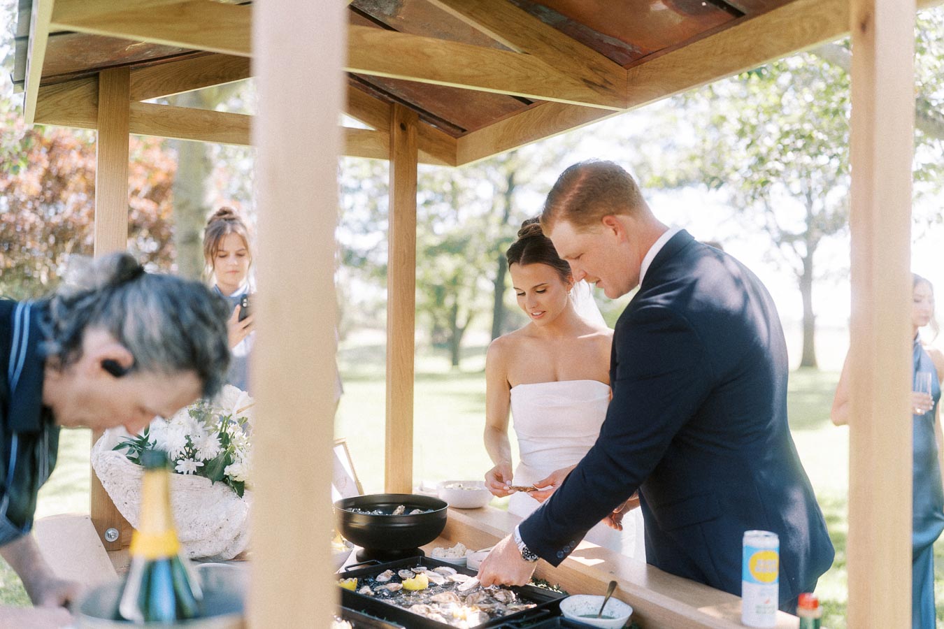 Bride and groom at an outdoor oyster bar during a private estate wedding near Chatham-Kent, Ontario, Canada.