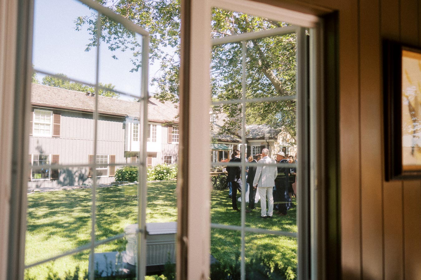 Outdoor wedding guests seen through a window at a private estate near Chatham-Kent, Ontario, Canada.