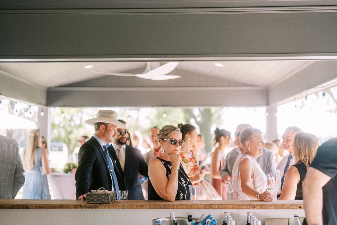 Wedding guests standing at an outdoor bar under a tent during a private estate farm wedding near Chatham-Kent, Ontario, Canada.