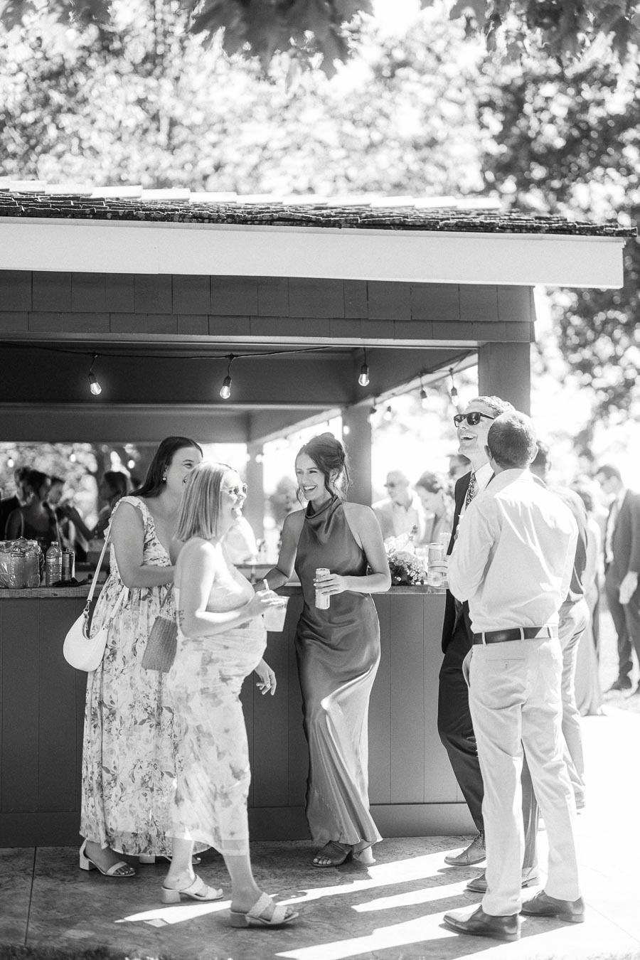 Black and white photo of wedding guests socializing at an outdoor bar during a private estate farm wedding near Chatham-Kent, Ontario, Canada.