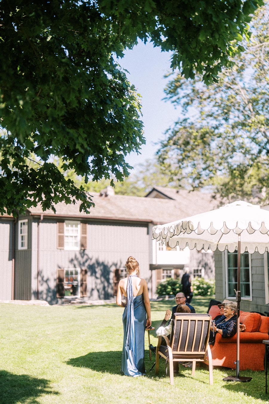 Outdoor wedding guests relax on a lawn under a white patio umbrella at a private estate near Chatham-Kent, Ontario, Canada.