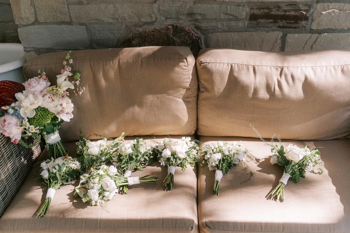 Wedding bouquets and white floral arrangements resting on a beige outdoor sofa near Chatham Kent, Ontario.