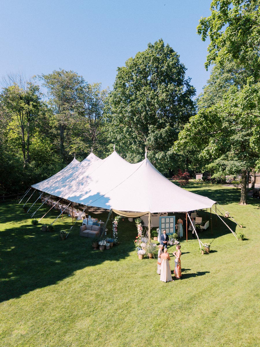 Outdoor private estate wedding tent on a green lawn near Chatham-Kent, Ontario, Canada, surrounded by trees on a sunny day.