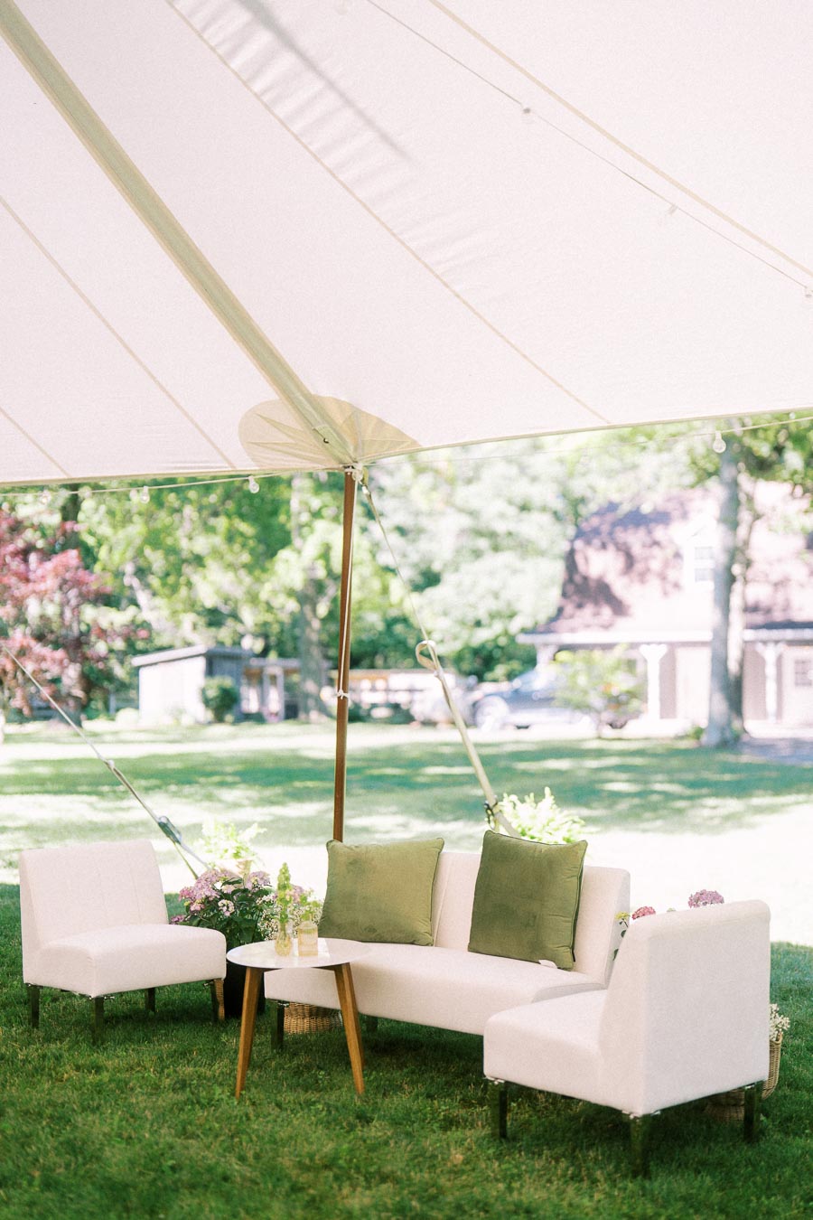 White lounge seating with green pillows under a wedding tent on a private estate lawn near Chatham-Kent, Ontario, Canada.