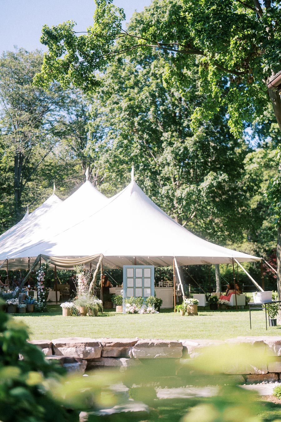 White wedding tent set on a green private estate lawn near Chatham-Kent, Ontario, with floral decor, trees, and summer sunlight.