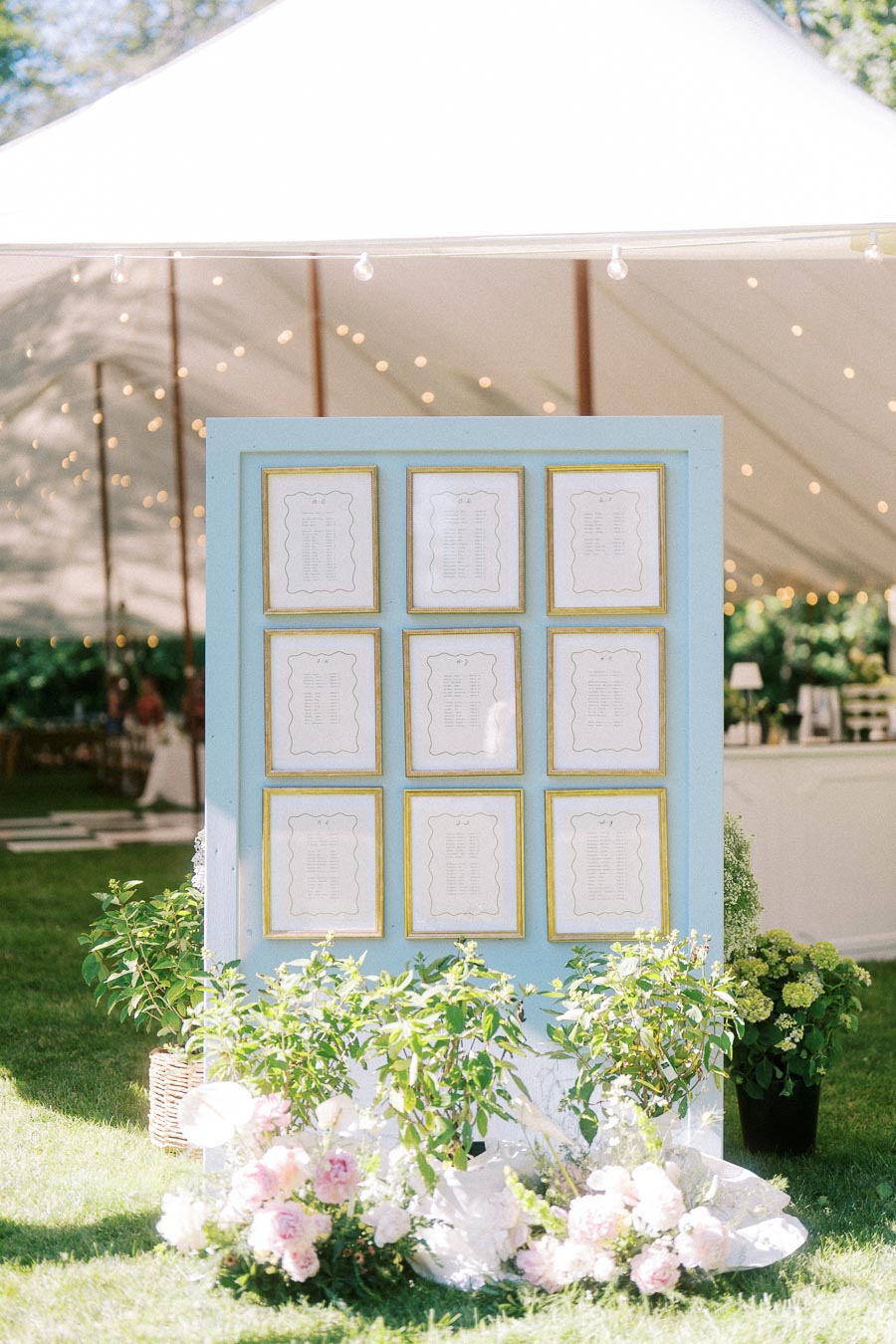 Outdoor farm wedding seating chart display with framed cards, flowers, greenery, and a white reception tent on a private estate near Chatham-Kent, Ontario.