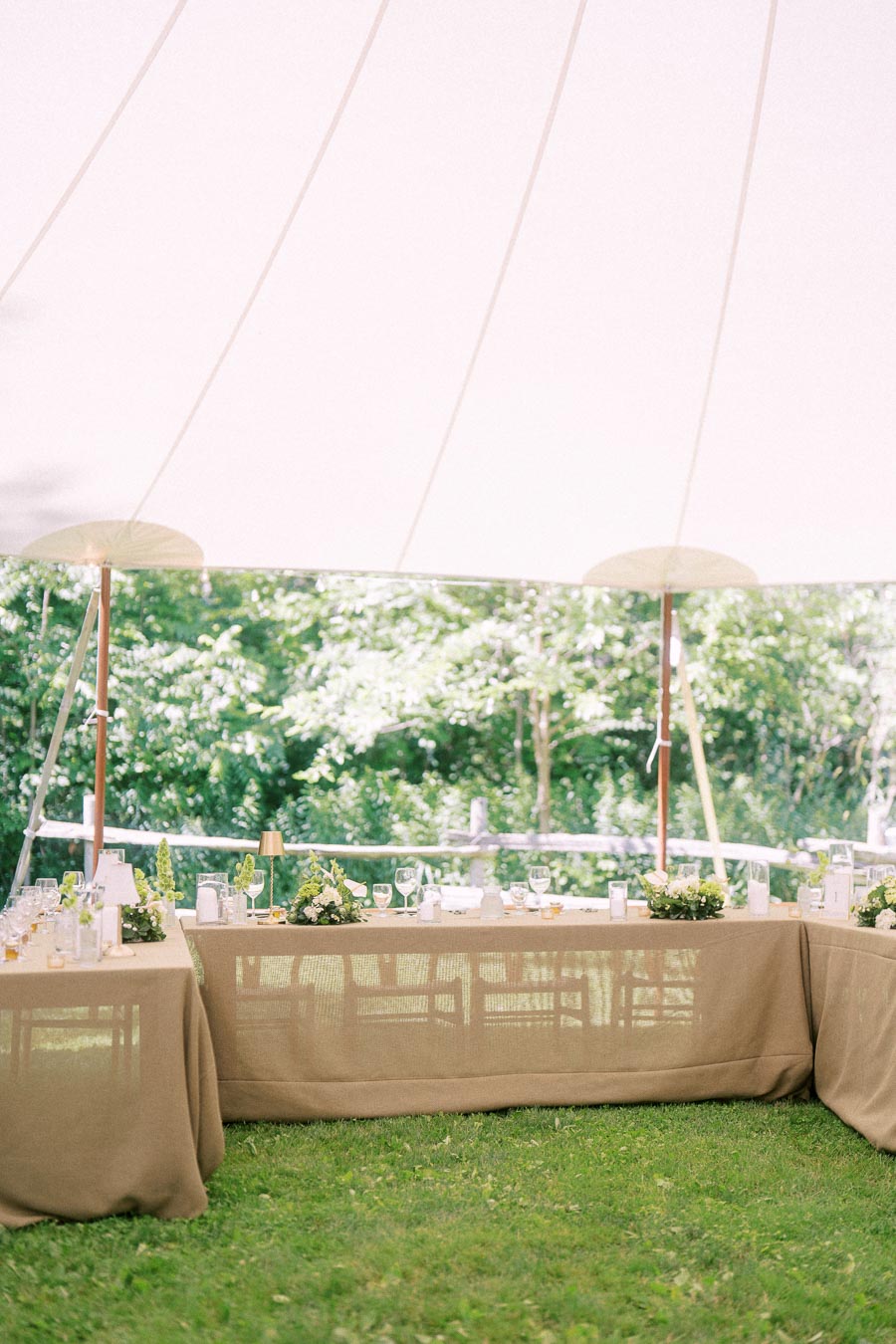 Outdoor wedding reception tables under a white tent on a private farm estate near Chatham-Kent, Ontario, Canada, with greenery and floral centerpieces.