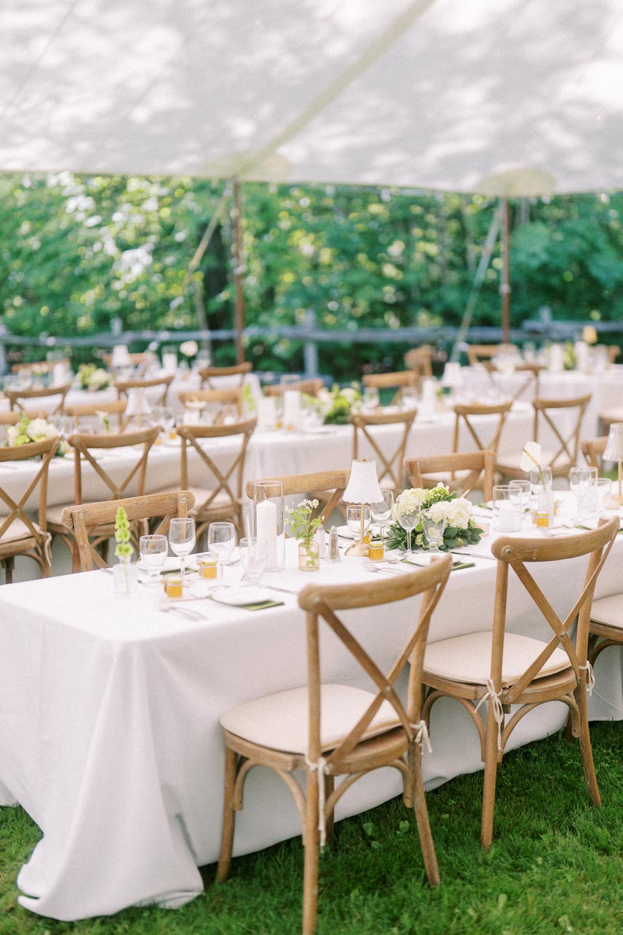 Outdoor tented wedding reception on a private estate near Chatham-Kent, Ontario, with white tables, wooden chairs, florals, glassware, and candles.