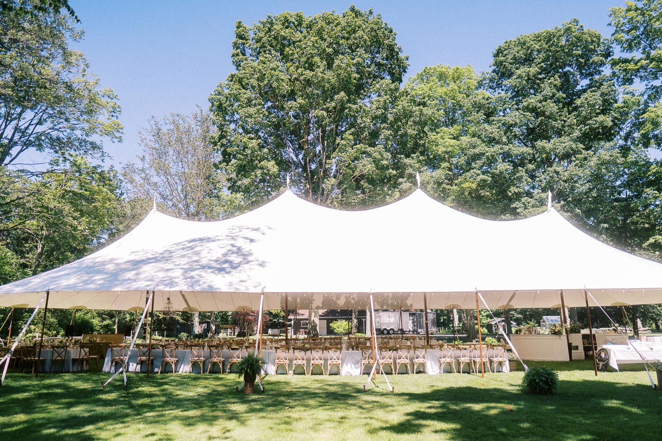 White wedding tent with dining tables and wooden chairs on a private farm estate lawn near Chatham-Kent, Ontario, Canada.
