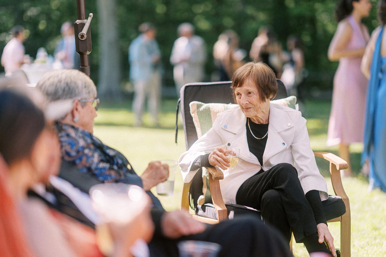 Elderly woman seated in a lawn chair holding a drink during an outdoor private estate wedding reception near Chatham-Kent, Ontario, Canada.