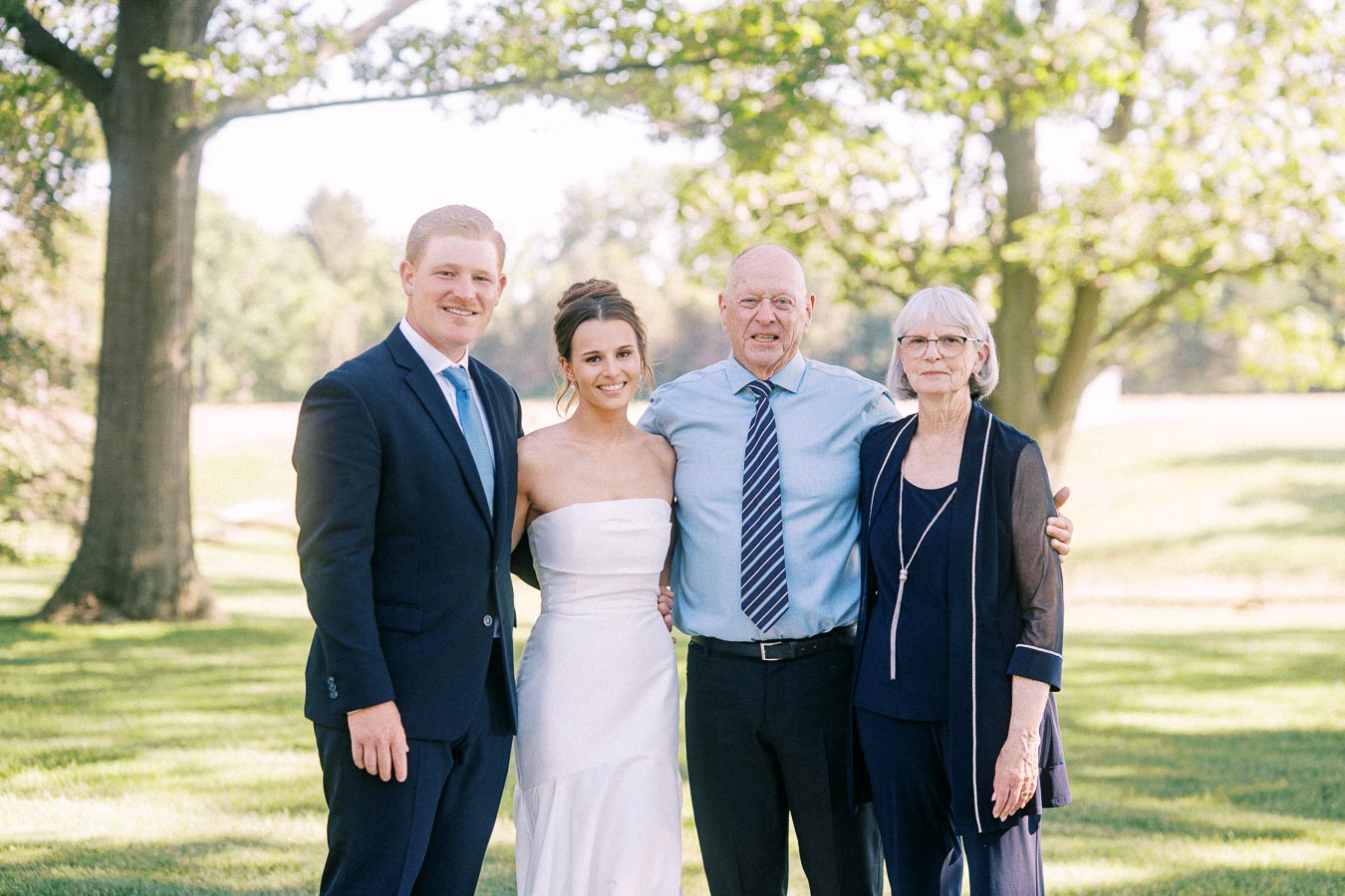 Bride and groom posing with older relatives on a sunny lawn during an outdoor private estate wedding near Chatham-Kent, Ontario, Canada.