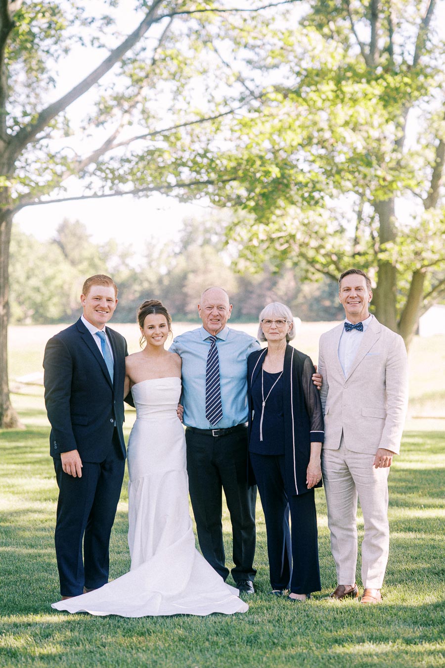 Bride with four family members posing for an outdoor wedding portrait on a grassy private estate near Chatham-Kent, Ontario, Canada.