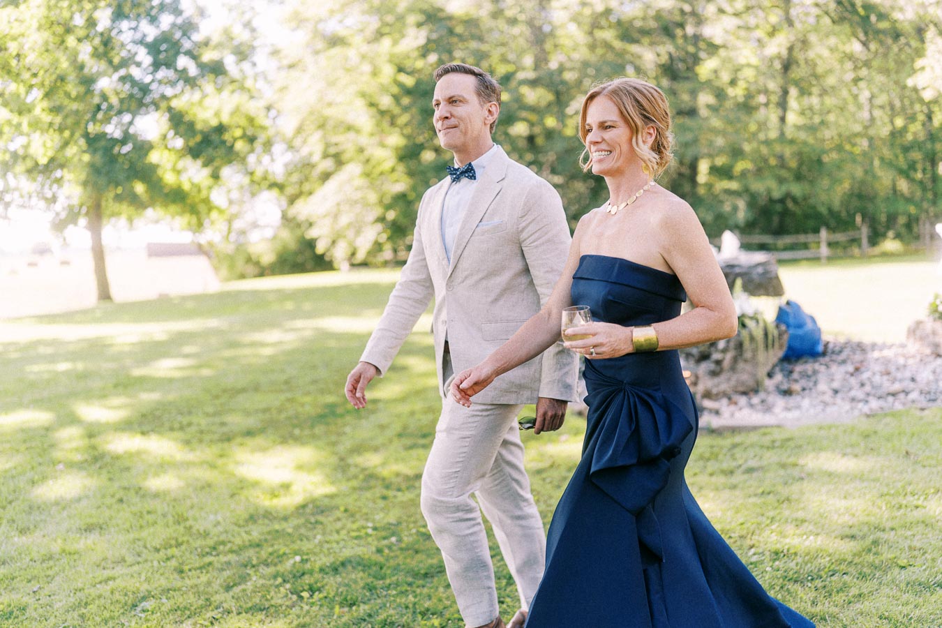 Wedding guests walking across a sunny lawn at a private estate outdoor wedding near Chatham-Kent, Ontario, Canada.