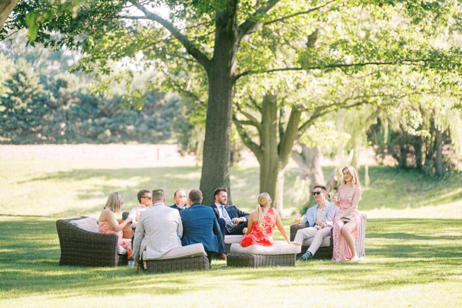 Wedding guests relaxing on outdoor lounge furniture under trees on a private farm estate near Chatham-Kent, Ontario, Canada.
