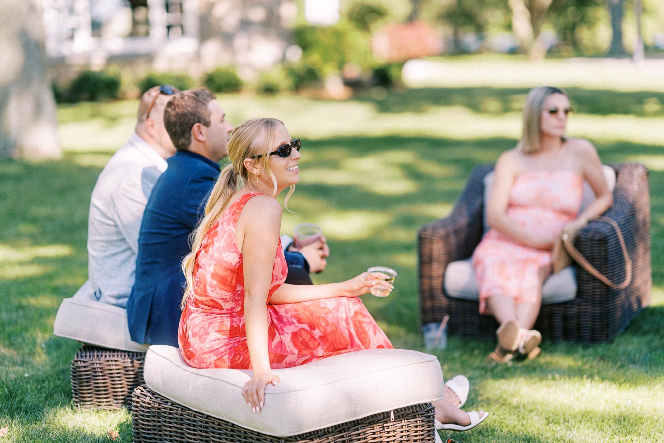 Wedding guests relaxing on wicker lounge seating outdoors on a private estate lawn near Chatham-Kent, Ontario, Canada.
