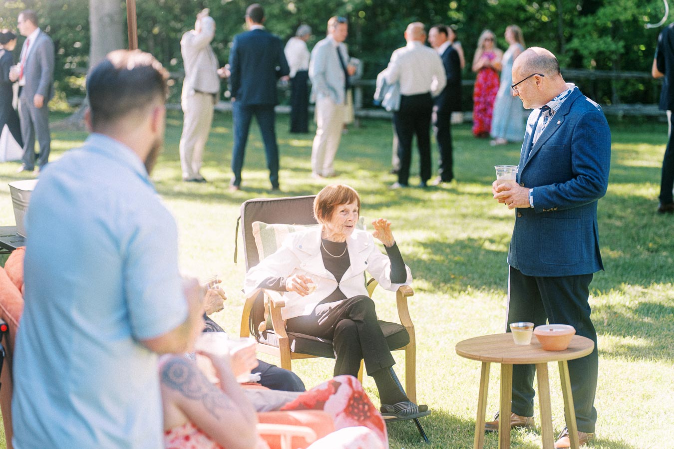 Wedding guests socialize on a sunny lawn at a private estate outdoor reception near Chatham-Kent, Ontario, Canada.