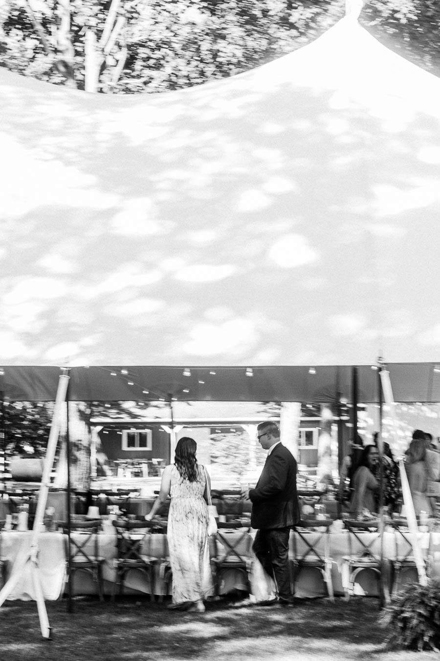 Black and white outdoor wedding reception tent on a private farm estate near Chatham-Kent, Ontario, with guests walking under a canopy.