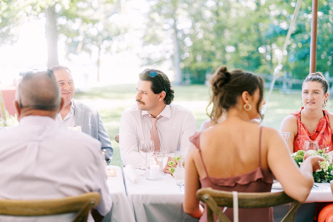 Wedding guests seated at a long table under a tent during an outdoor farm reception near Chatham-Kent, Ontario, Canada.