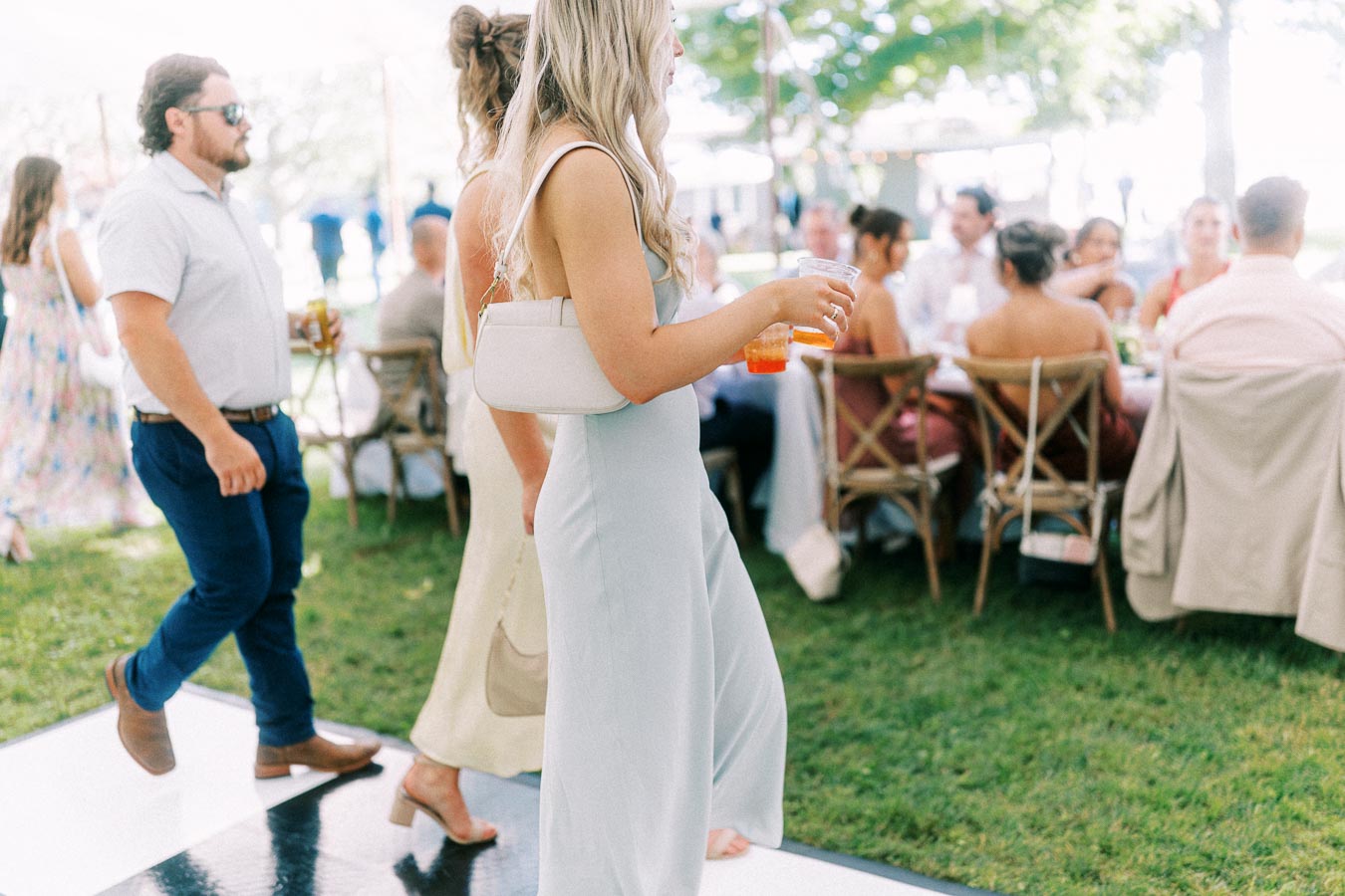 Wedding guests mingle outdoors under a tent at a private estate farm wedding near Chatham-Kent, Ontario, Canada.