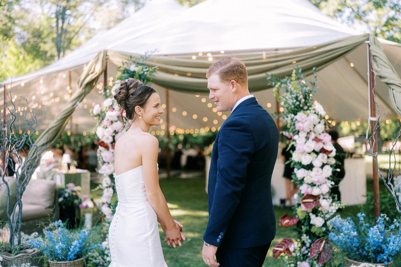 Bride and groom holding hands outside a decorated wedding tent on a private estate near Chatham-Kent, Ontario.