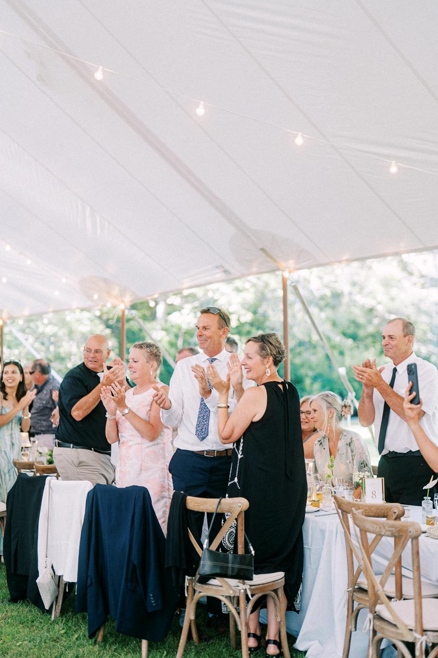Wedding guests applauding under a white reception tent at a private estate farm wedding near Chatham-Kent, Ontario, Canada.