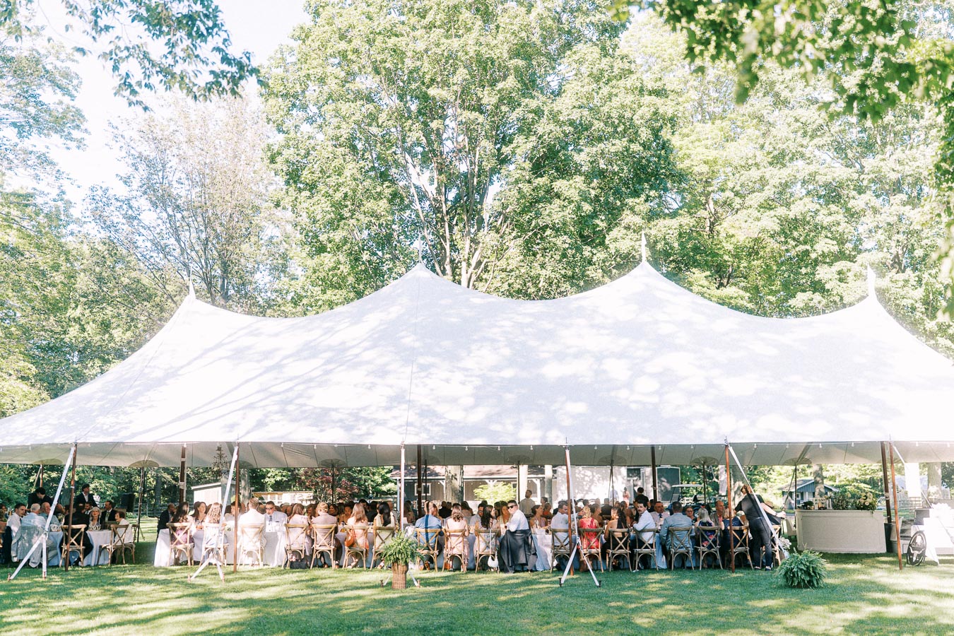 White wedding reception tent with guests dining outdoors on a private farm estate near Chatham-Kent, Ontario, Canada.